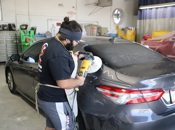 Auto body technician using buffer tool to repair dent on vehicle in Las Vegas